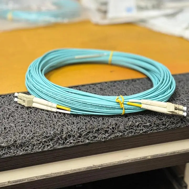 Turquoise fiber optic cable on a black foam block with blurred background